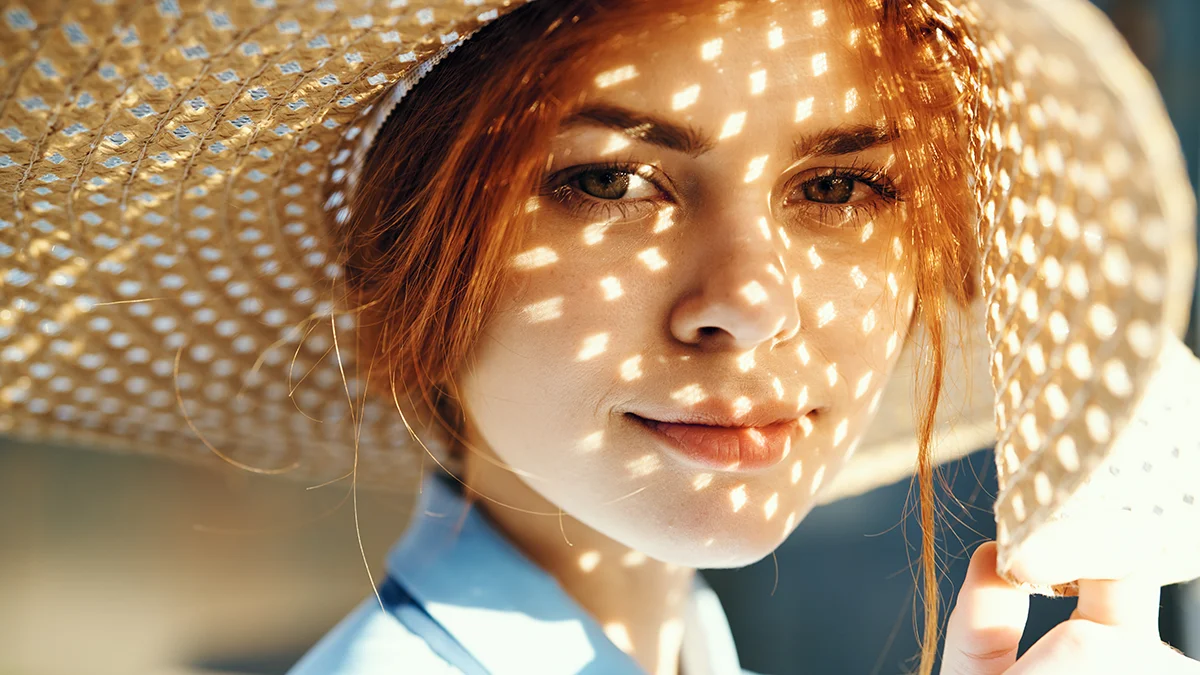 A woman protecting her skin barrier with a sun hat